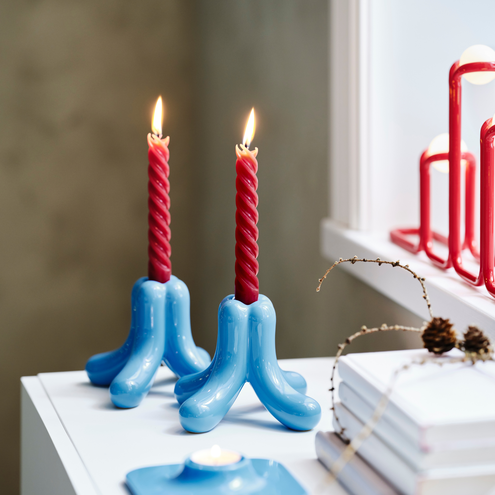 Red candle sticks in blue IKEA X Gustaf Westman candle stick holders.