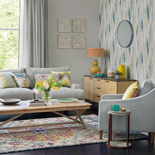 Grey colored living room with a grey sofa and curtains and colorful pillows and décor