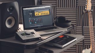 A studio setup with audio interface, studio monitors, electric guitar, and some studio microphones