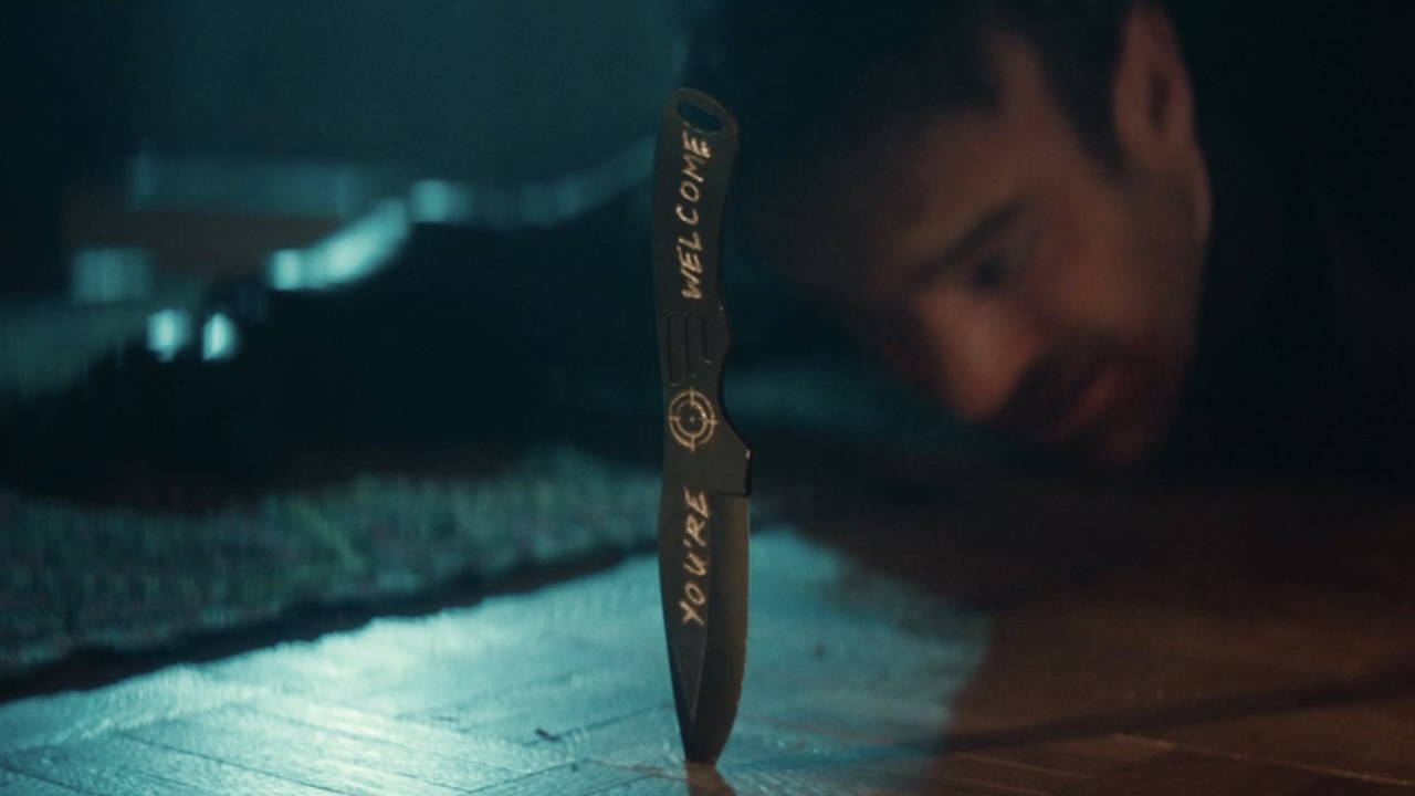 Bullseye's knife sticking out of the ground with &amp;quot;You're Welcome&amp;quot; written on it as Matt Murdock is lying in the background