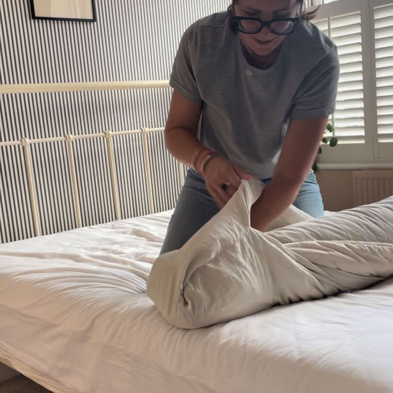 A woman putting a duvet cover onto a duvet using the 'burrito' method