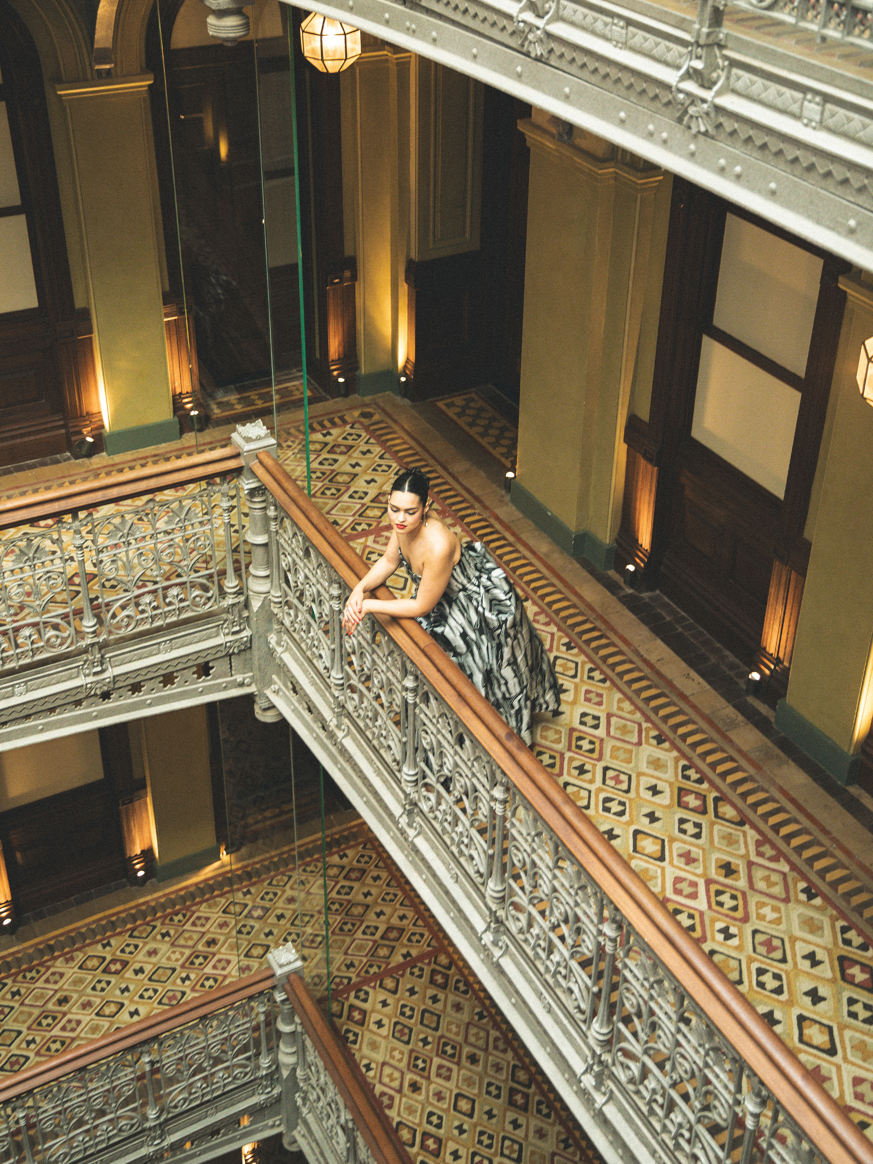 A bird's-eye view of Anna Lambe leaning on the railing in her hotel.