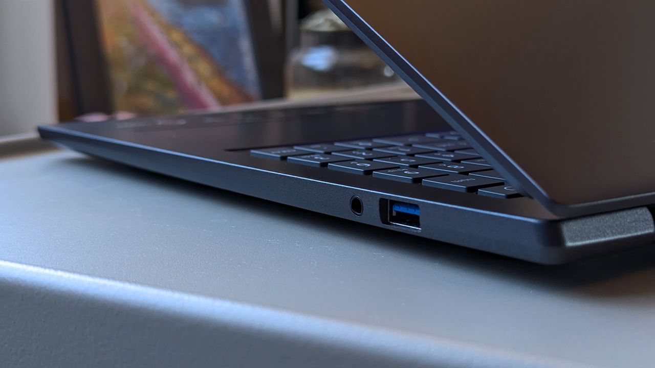 A close-up of a partially open Acer Swift laptop highlighting a USB port and audio jack on the right side. The keyboard and slightly tilted screen are visible, with blurred d&eacute;cor in the background.