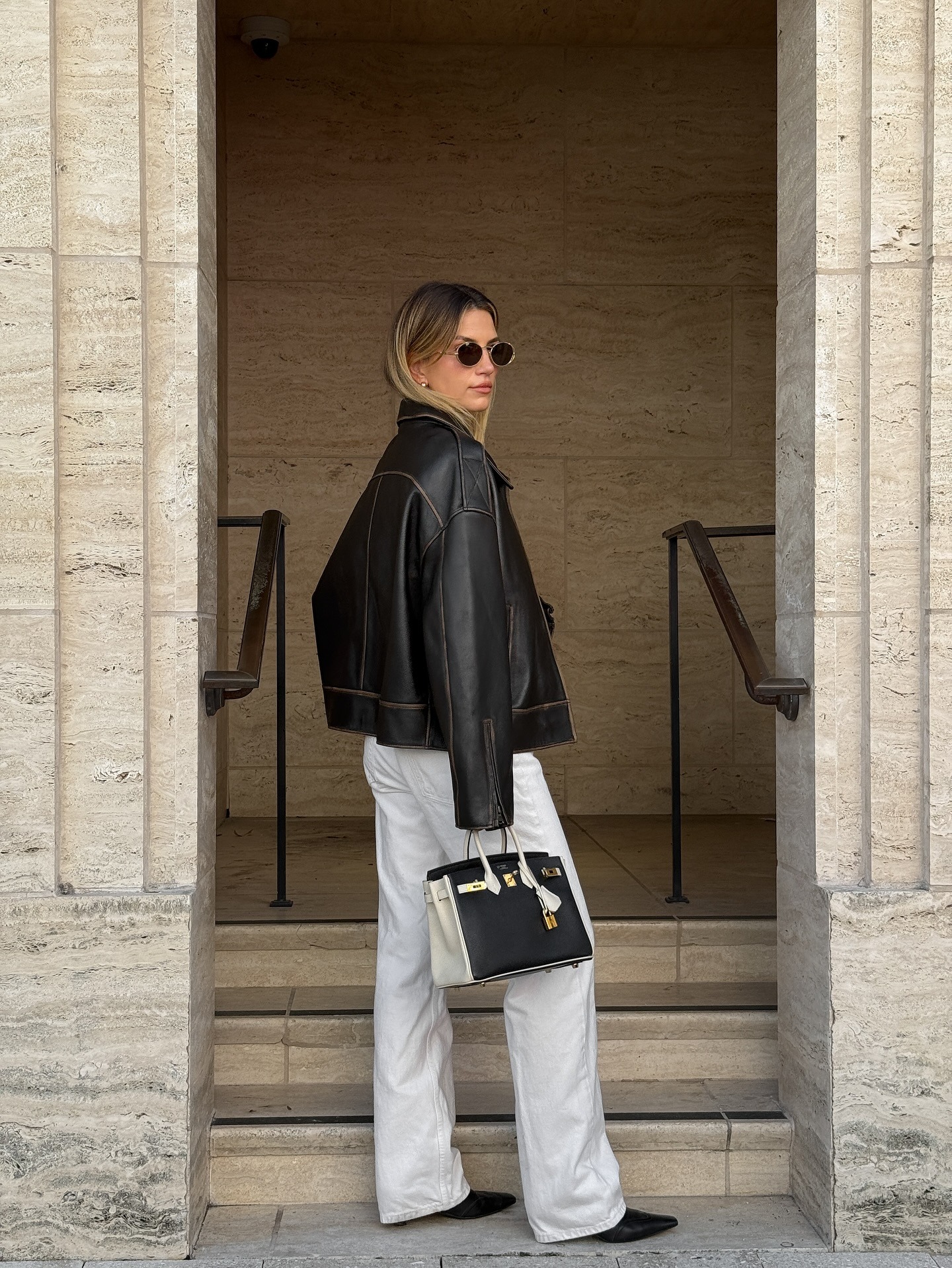 Woman wearing white jeans with brown bomber jacket and pointed boot shoes.