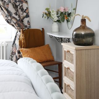 Bedroom with dresser unit, vases, armchair, decorative mirror on wall