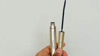 A person holding an opened L'Oreal Telescopic Mascara tube, for L'Oreal Telescopic Mascara review.