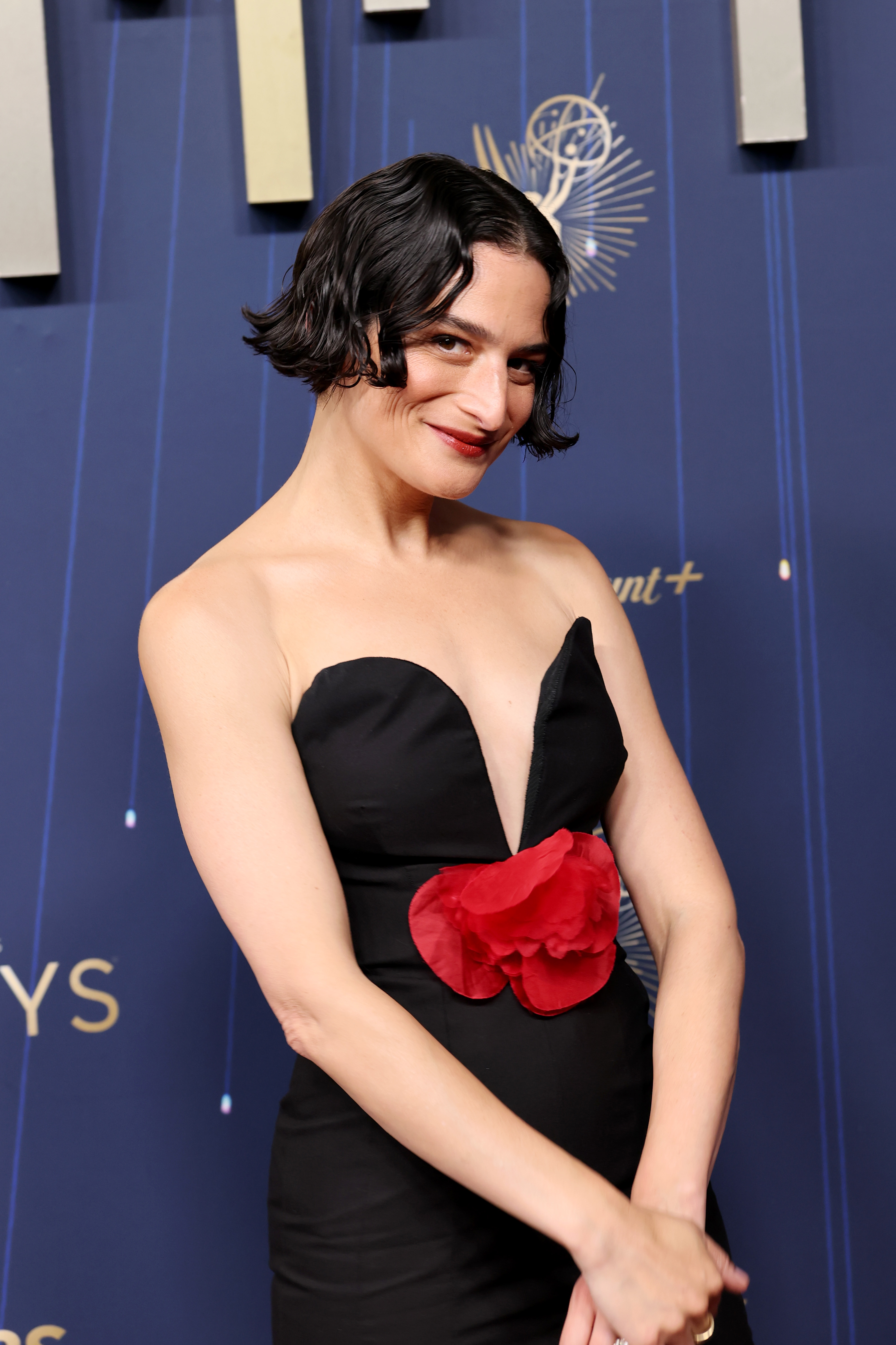 Jenny Slate wearing a red and black gown and short brown bob