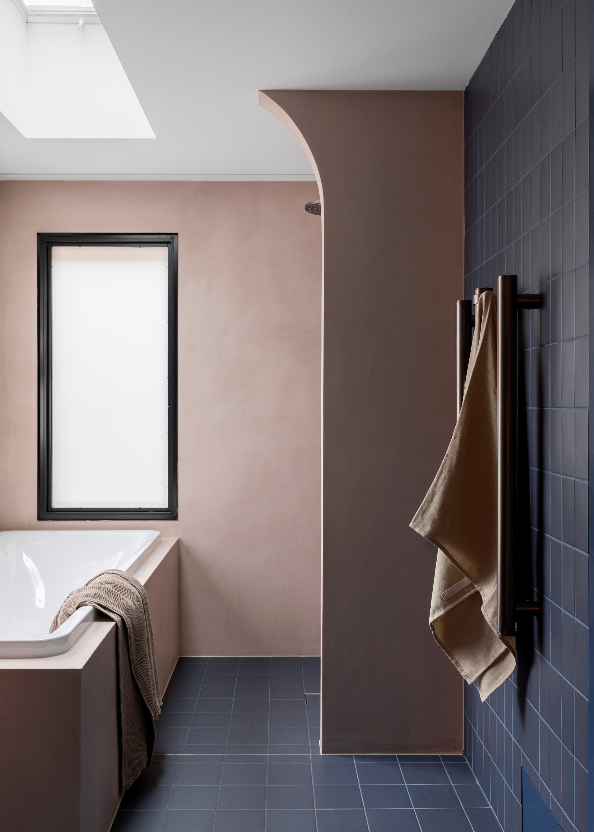 A bathroom with blue tiles, pale pink walls and a bathtub