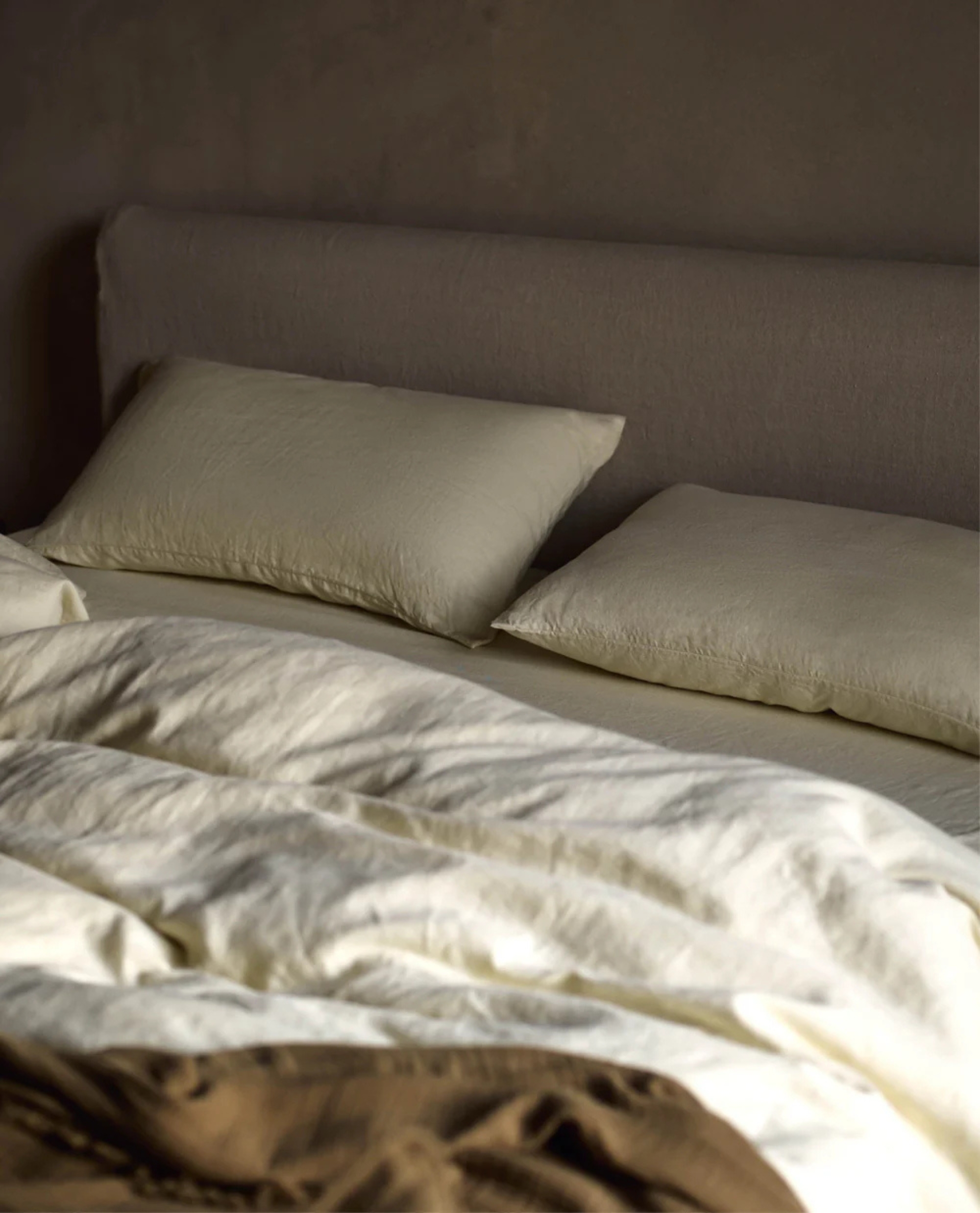 a bed with zesty green bedding and a linen headboard