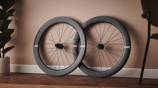 A pair of Enve 65 road bike wheels leans against a terracotta wall
