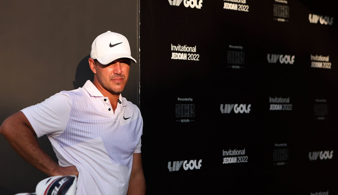 Koepka leans against an LIV Golf board