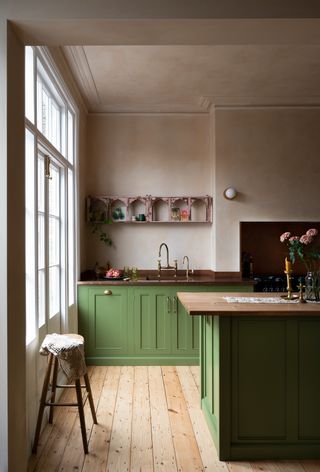 A kitchen with green cabinets, and a wooden countertop