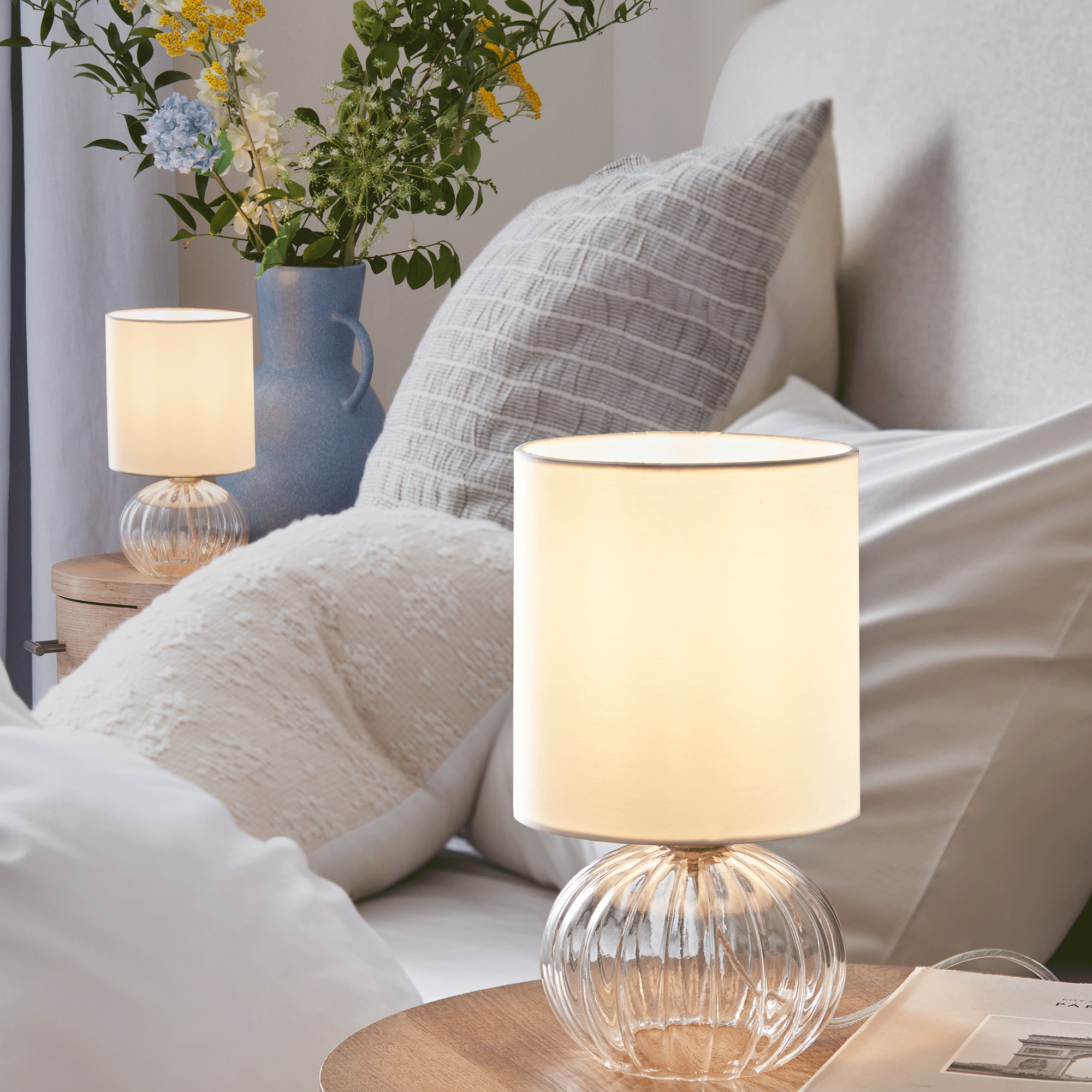 Lamps on bedside table with blue bedding
