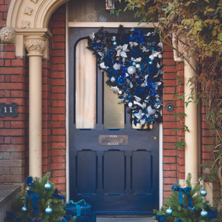 Front door of red brick house with asymmetrical christmas display
