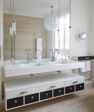 A neutral bathroom with a white double vanity, large spherical white chandelier