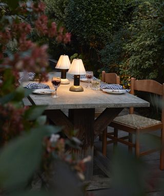 Dusk dining table outside with LED table lamps glowing whilst rest of shot is dark