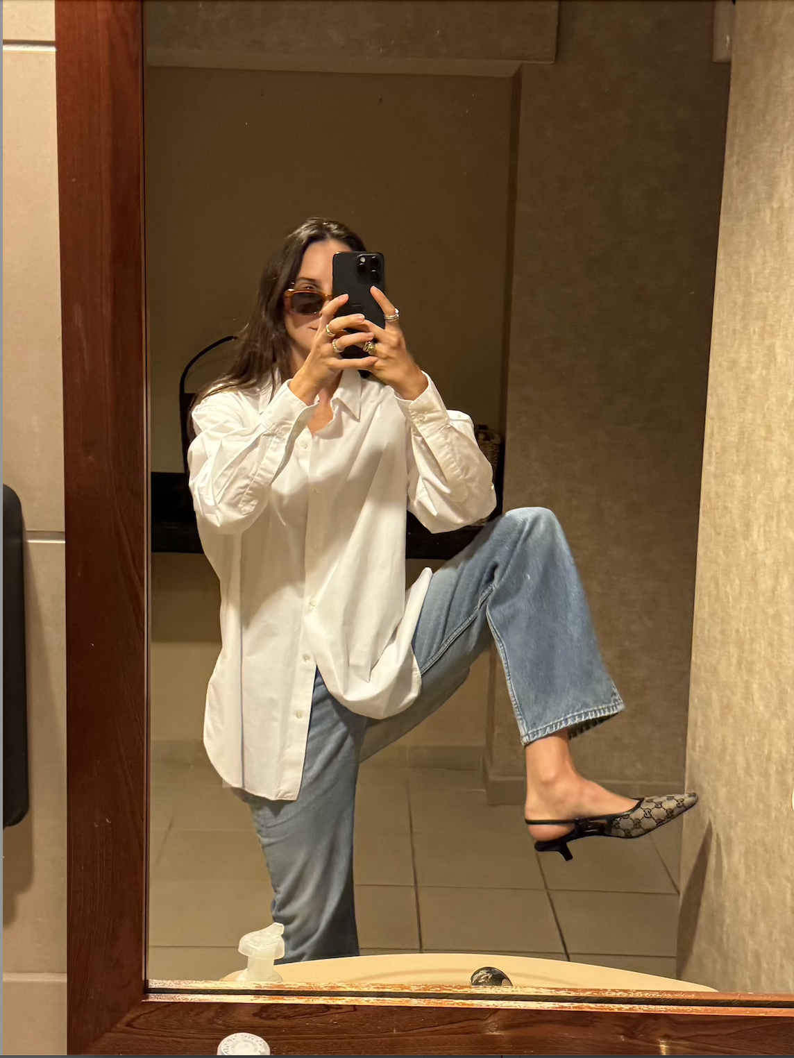 Rachel Whitehouse wears a white button down, jeans, and gucci heels in mirror selfie