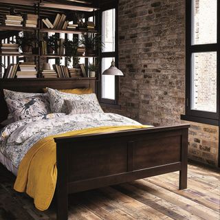 bedroom with brick wall wooden bed on wooden floor with book shelves