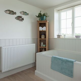 bathroom with bathtub and white wall and wooden floor