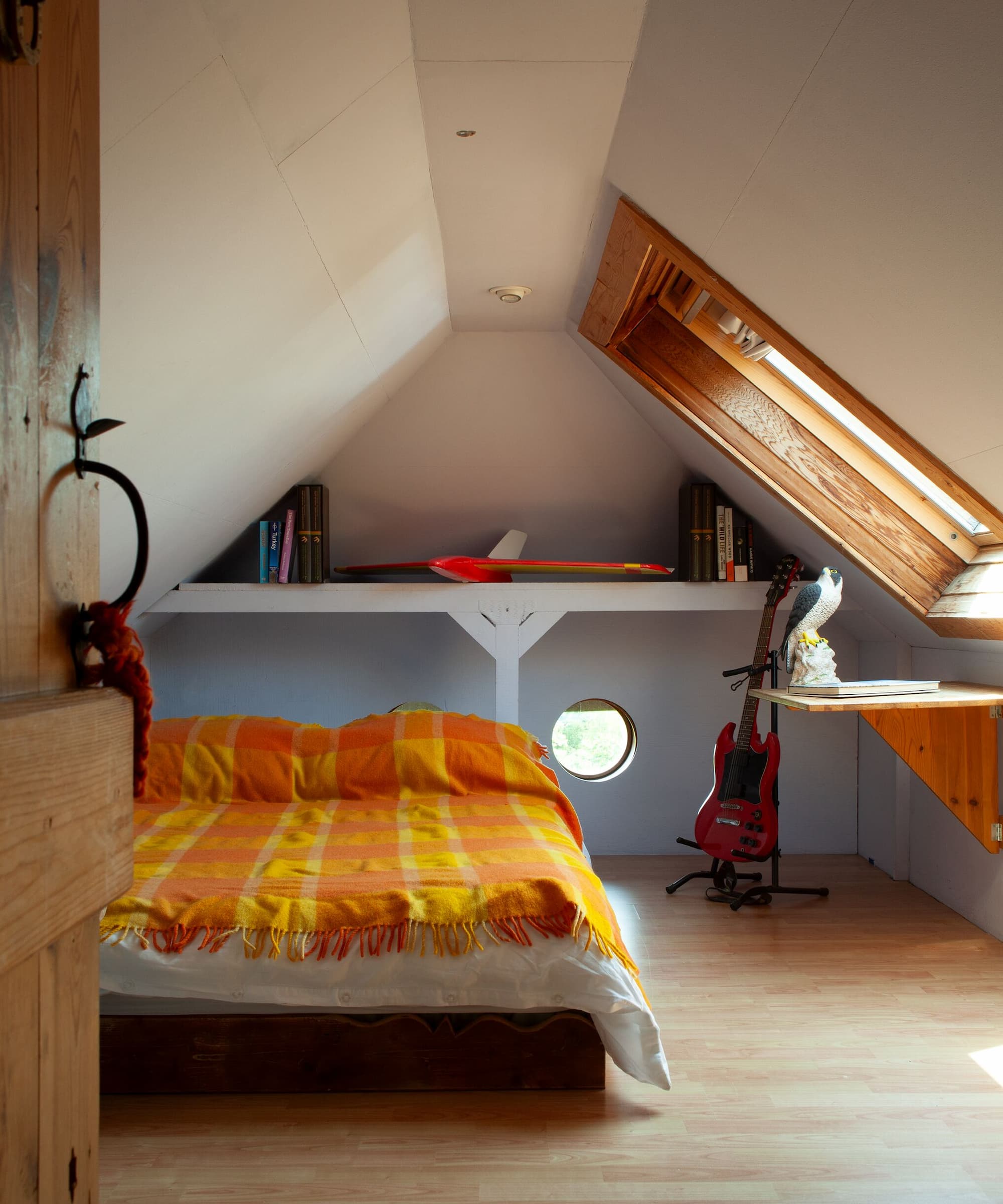 A bedroom with slanted ceilings and a dormer loft window