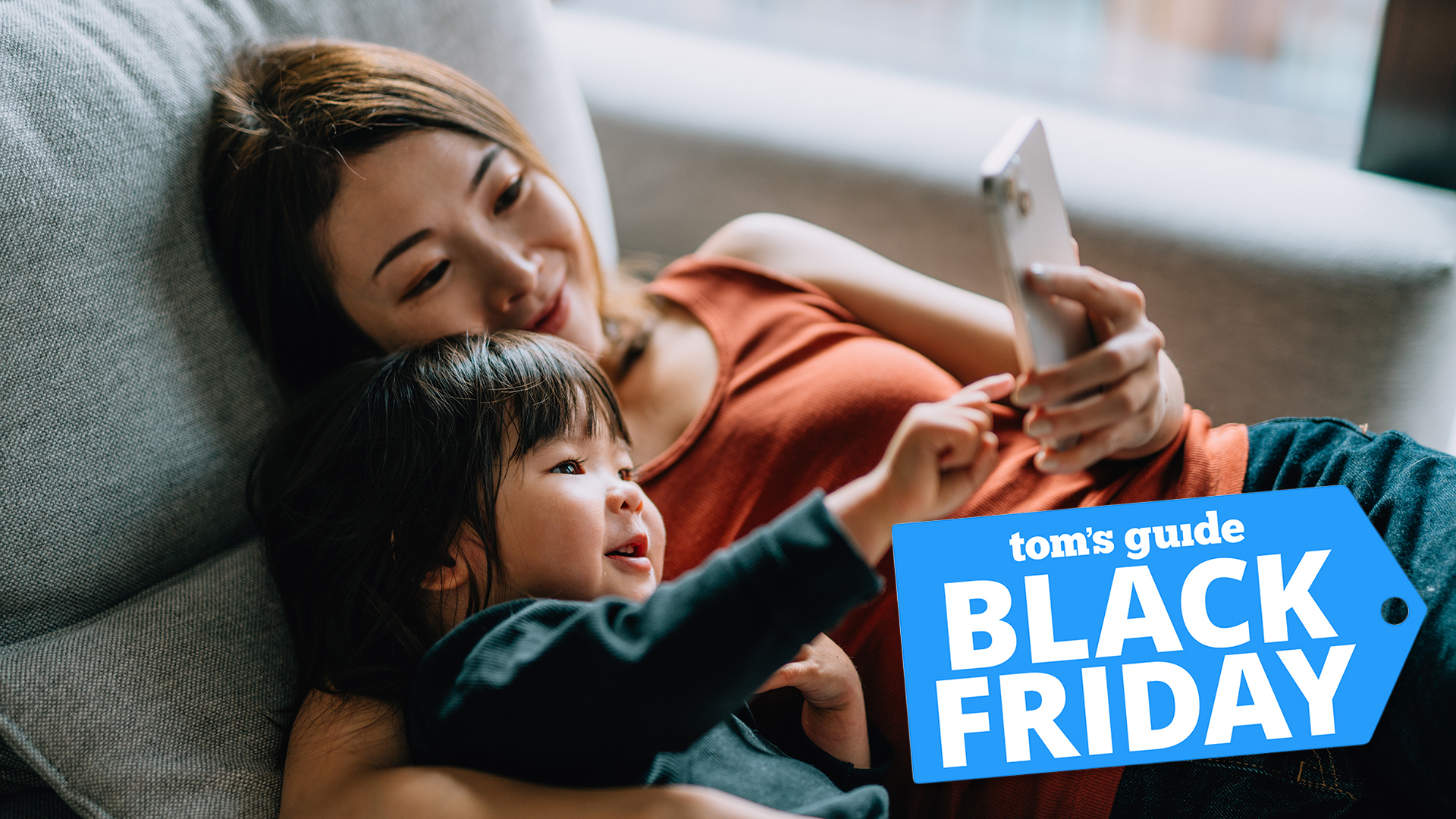 Woman and child on sofa looking at phone with Black Friday badge overlaid