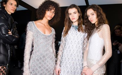 Models wear bright white shimmery dresses with hexagonal patterns and bead embellishments