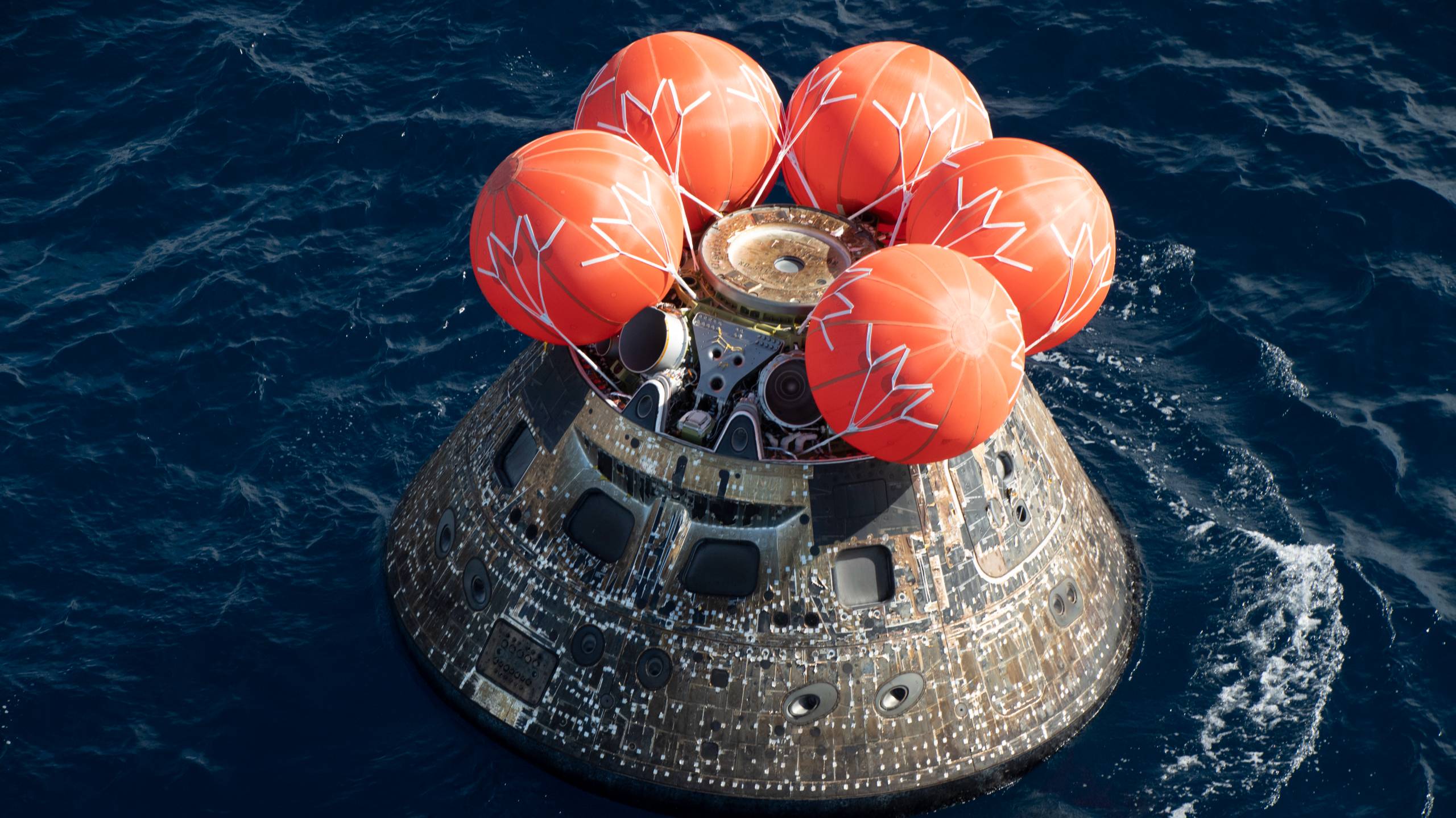 a cone-shaped spacecraft in the ocean with three inflatable balloons on top