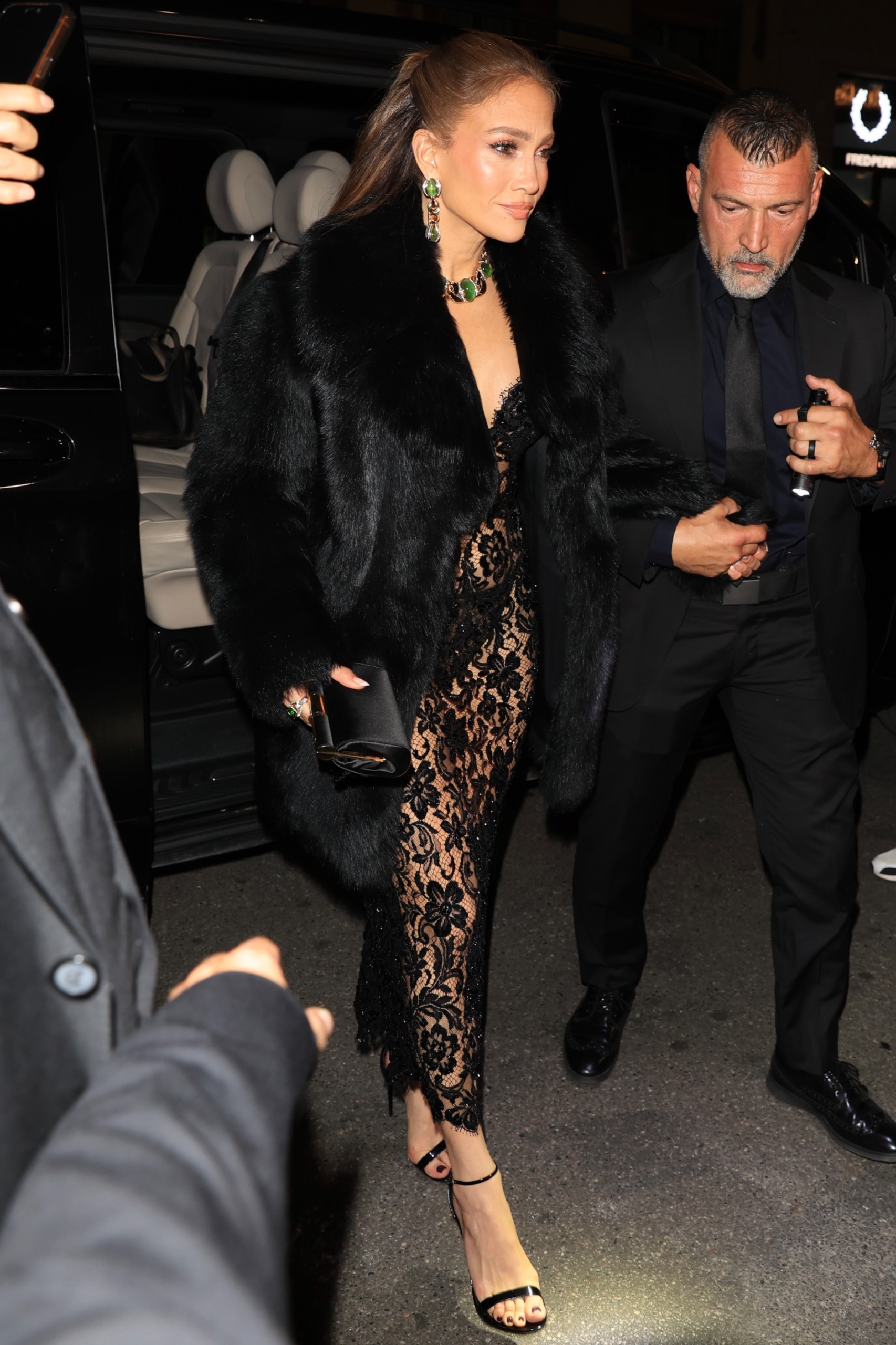 Jennifer Lopez in Milan wearing a black lacy lingerie slip as a naked dress with a fur coat to attend a Dolce and Gabbana party