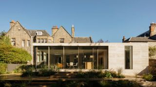 modern extension with stone and glass exterior attached to large period property