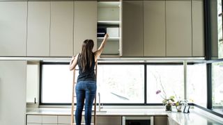 woman using ladder to reach high kitchen units