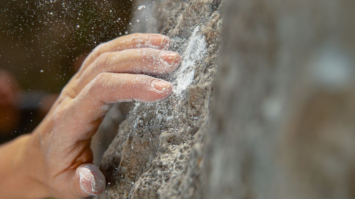 A close up of a climber&#039;s hand as they slip off the rock