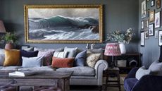 Sitting room detail with wooden floor and seascape painting over grey sofa