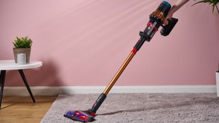 Dyson V16 Piston Animal cordless stick vacuum being used on a rug in a living room