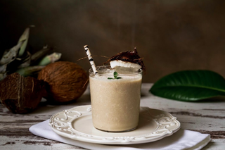 Fresh coconut and pineapple smoothie in a glass with a paper straw