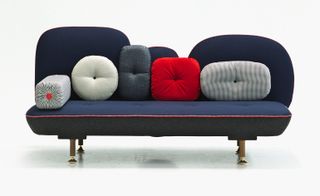 Dark blue sofa with five different shaped and coloured cushions