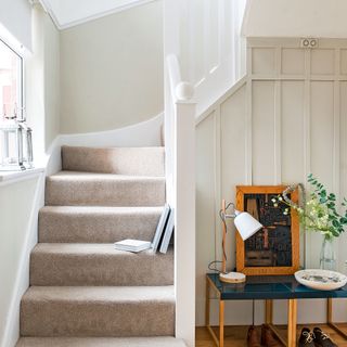 Neutral hallway with beige carpeted stairs and traditional wall panelling painted off white
