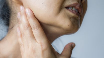 Woman holding jaw, representing menopause and tooth pain