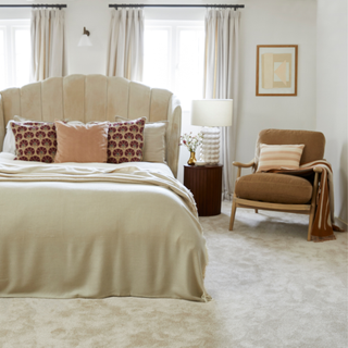 A neutral bedroom with large double bed with headboard and plush cream carpet on the floor