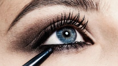 Close up of eyeliner being applied to young womans eye - stock photo