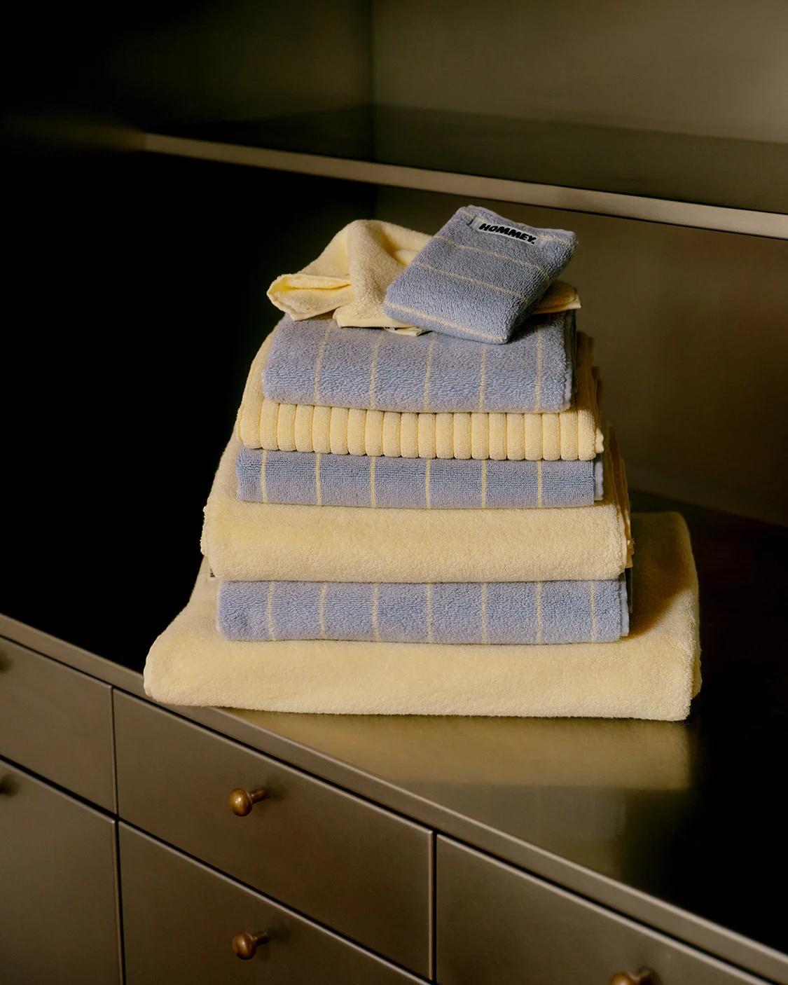 Image of a stack of light yellow and light blue bath towels on a chrome wardrobe.