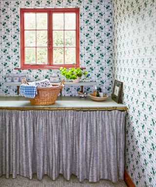 utility area with patterned wallpaper and curtain below sink and worktop