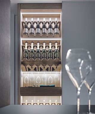 A slimline wine storage display case with bright white LED lighting showcasing bottles and glasses