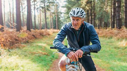Older man on a bike in the woods.