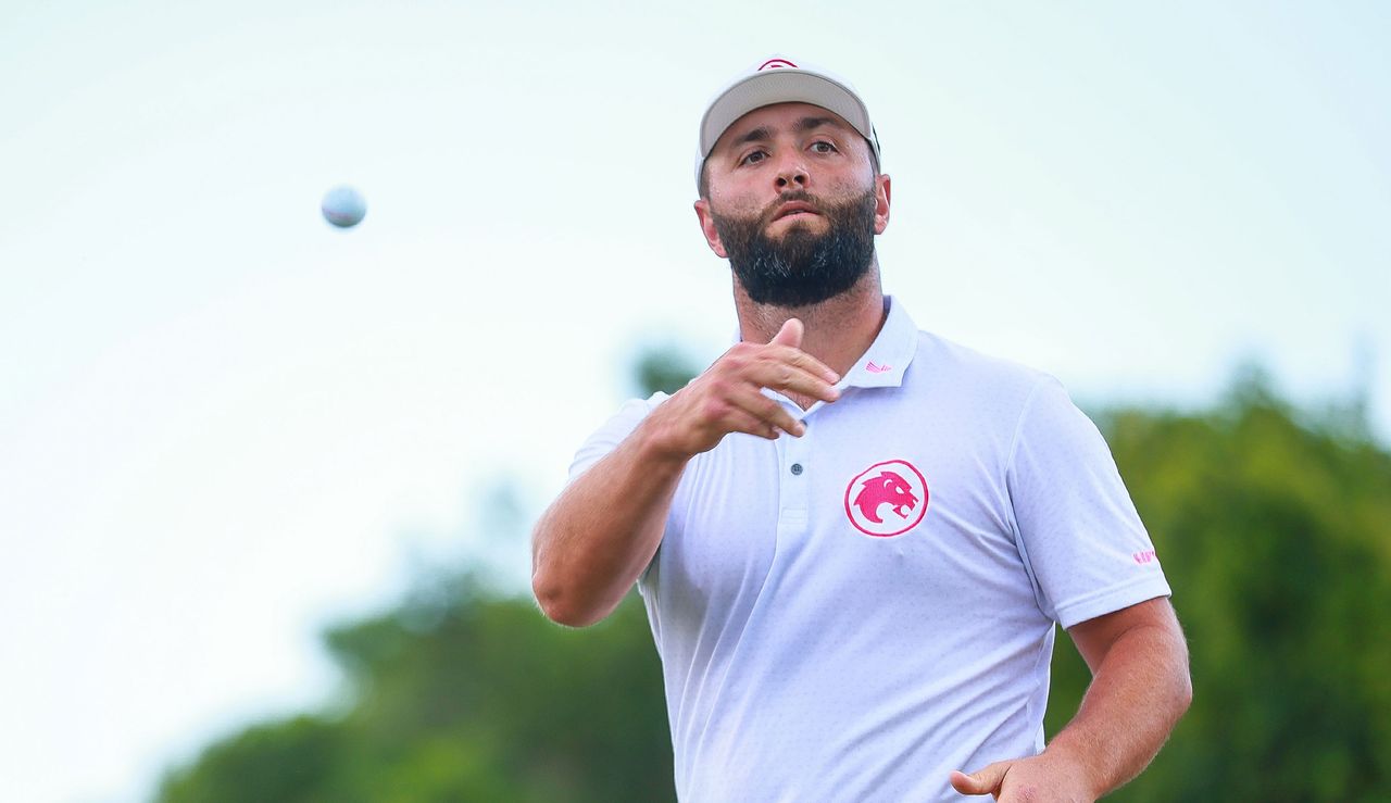 Jon Rahm throws a golf ball to a spectator 