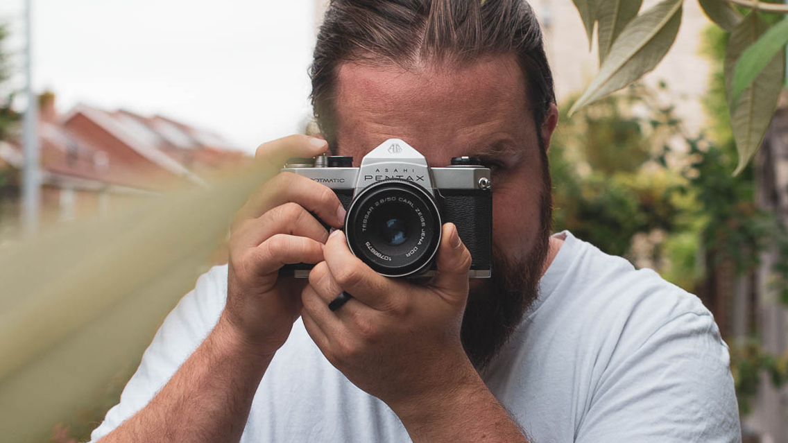 A man holding a retro film camera up to his eye