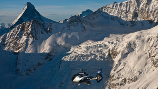 A helicopter flies through the Alps