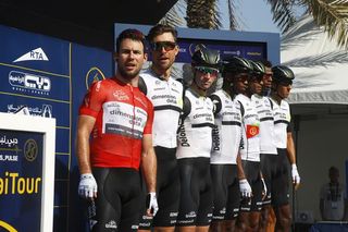 Mark Cavendish stands next to his Dimension Data team wearing the red jersey at the Dubai Tour