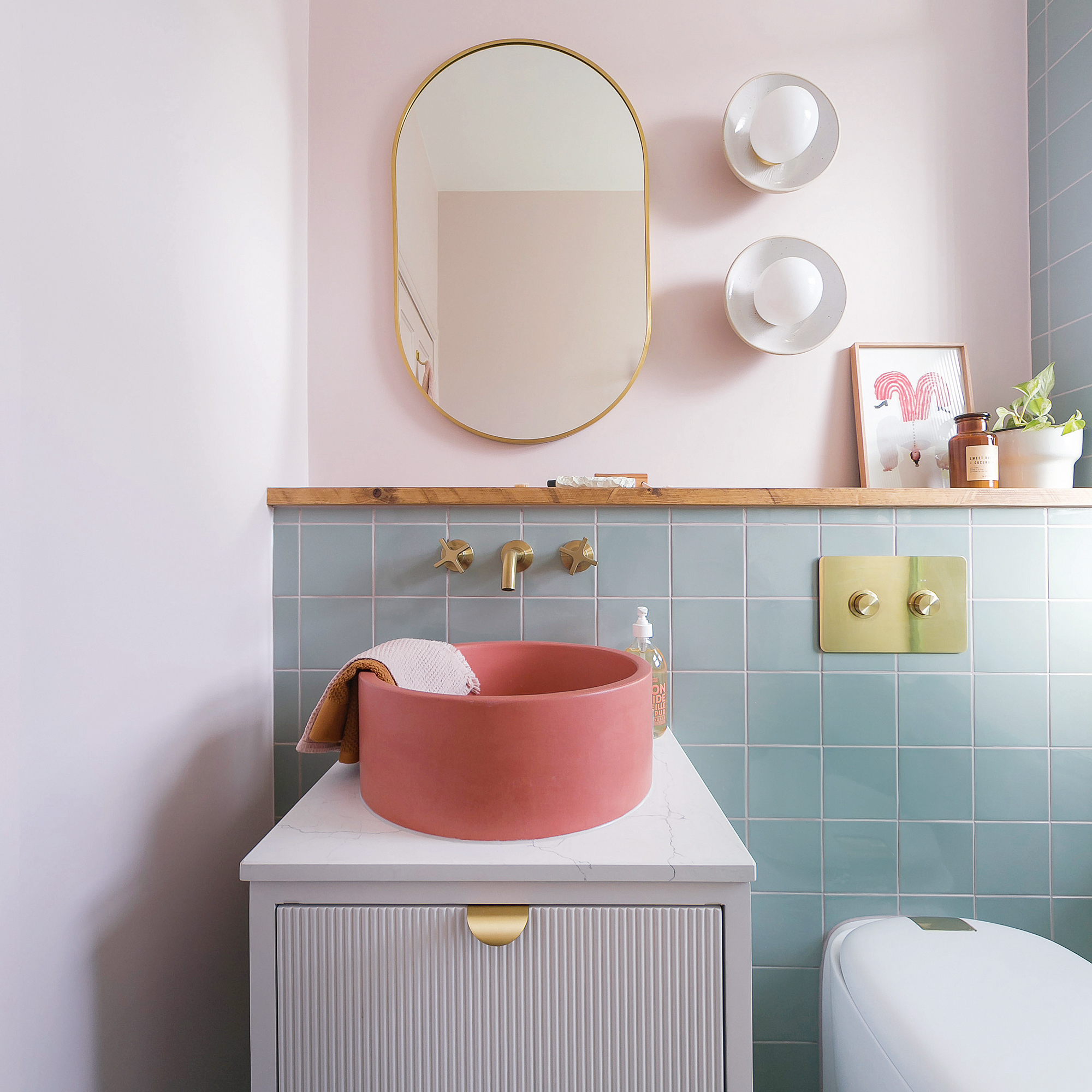 a small bathroom with green wall tiles and a bright coral modern bowl basin