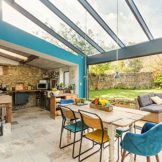 A large dining area with a kitchen under a conservatory style roof