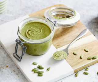 Jar of pepita pesto on counter with pepitas